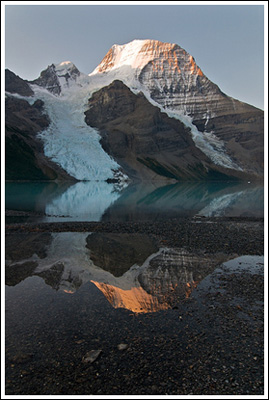 Sunrise lights up the top of Mt. Robson, reflected.